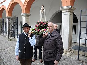 Vier Kandidaten tragen die Statue der "Rosa Mystica"